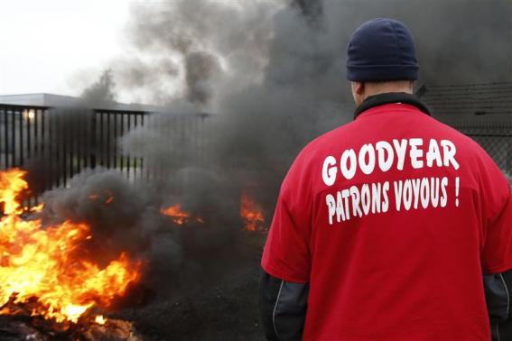 File picture of an employee of US tyre-maker Goodyear standing in front of burning tires at the entrance of the plant in Amiens, northern France